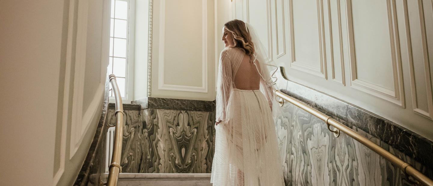 Bride walking up marble stairs of the Circular Hall showing the back of her wedding dress