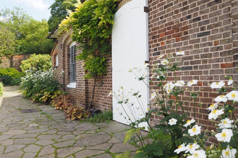 Back entrance to the Brockwell Folly showing white door leading to the Walled Garden with flowers and foliage 
