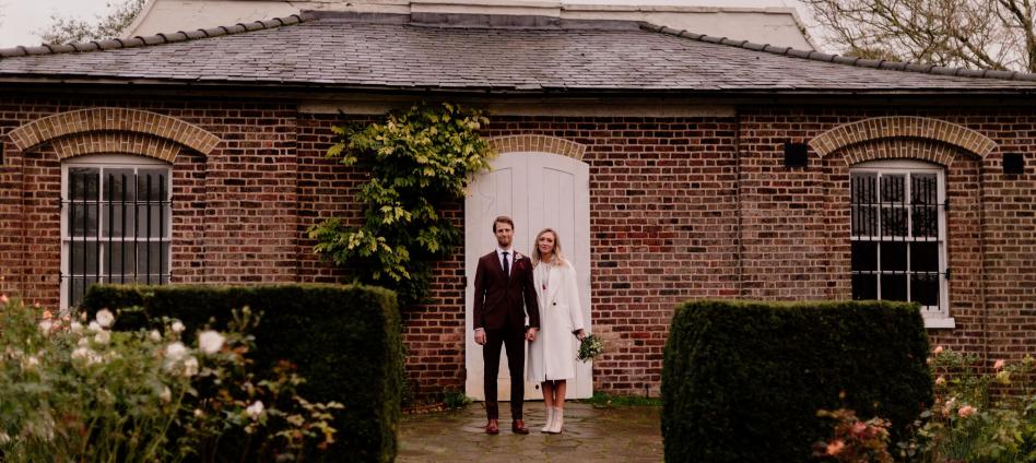 Couple standing in front of a white door of Brockwell Folly within gardens 