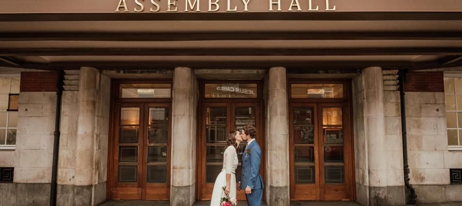 bride and groom kiss outside Assembly Hall entrance