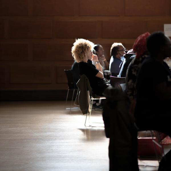 Audience member engaged with event with spotlight reflecting shadows onto wooden floor