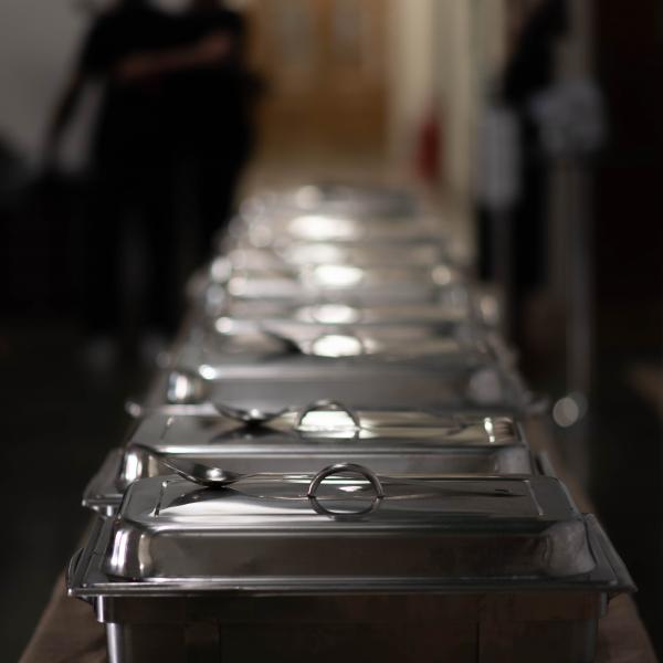 Image of a row of chafing dishes on a catering table with light hitting the lids