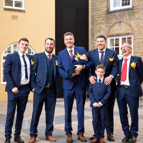 Groom stands with groomsmen and family members laughing and smiling in Lambeth Town Hall courtyard