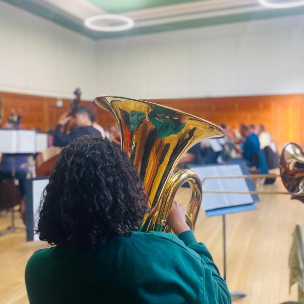 woman wearing green top playing brass instrument 